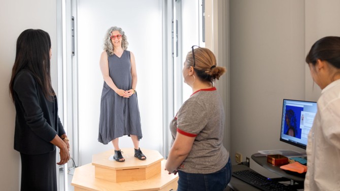 Study participant Hale Tufan, associate professor in the School of Integrative Plant Science in the College of Agriculture and Life Sciences, stands in the body scanner at the Fashion and Body Tech Lab in the College of Human Ecology. Helping to prep the scan are entrpreneur Saira Patel (left), Fatma Baytar, Ph.D. ’11, (center right), assistant professor of human centered design in the College of Human Ecology, and graduate student Yoon Yang, M.A. ’22, (right).