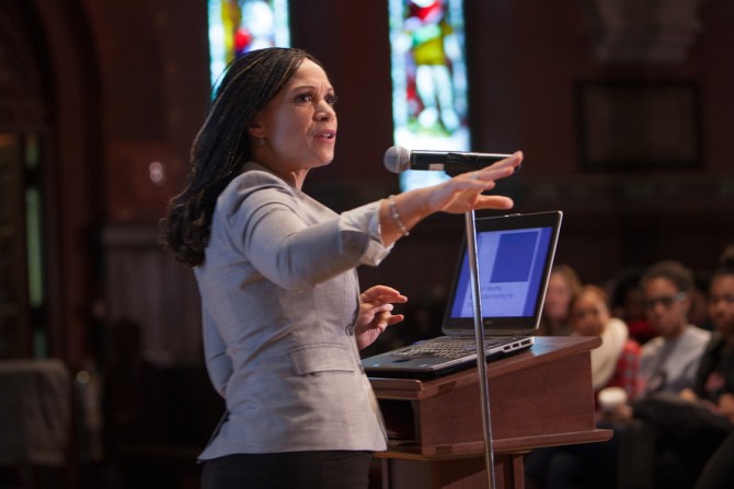 Person speaking at a podium, with stained glass windows in the background