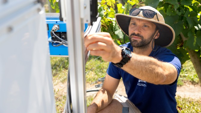 Robotics technician Cole Regnier works on an autonomous robot designed to detect disease on grapevines on the Cornell AgriTech campus in Geneva, New York.