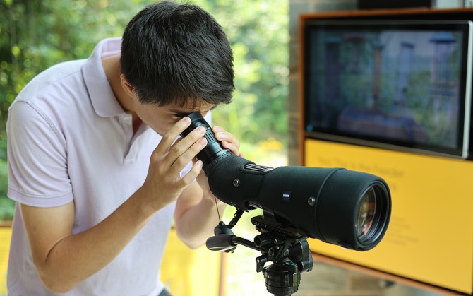 Everett Smith ’27 looks through binoculars at the Lab of Ornithology Visitor Center