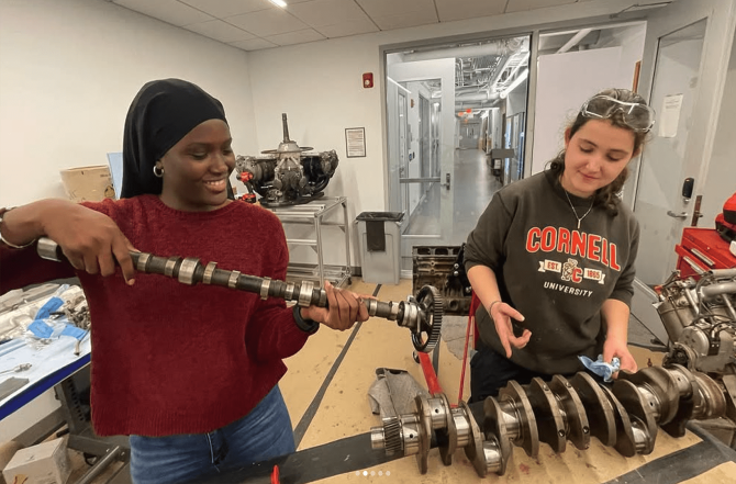 Two students dissect machinery in a fluid mechanics course.