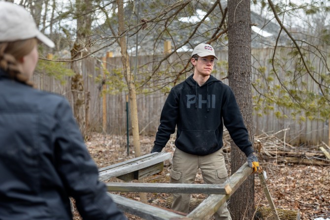 two students carry a wooden structure