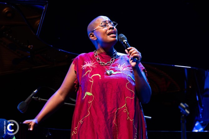 Person wearing a red dress singing with a microphone