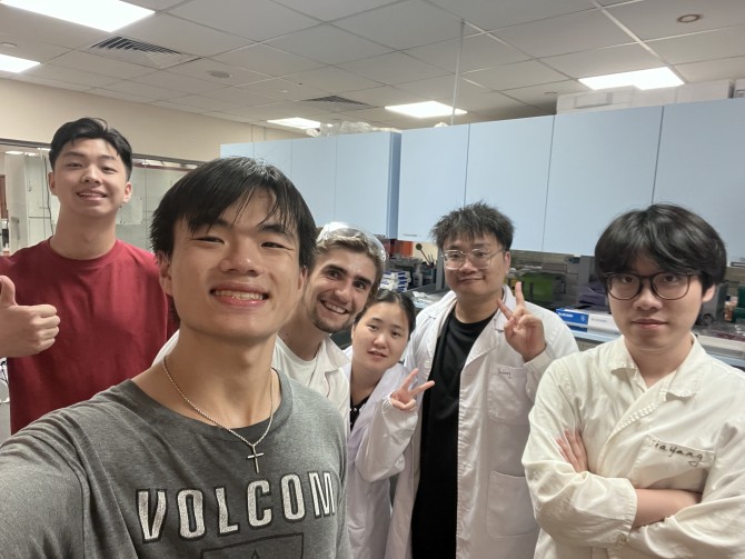 Frank Fang and his labmates take a selfie in their lab coats.