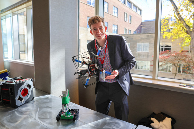 student stand holding a robot