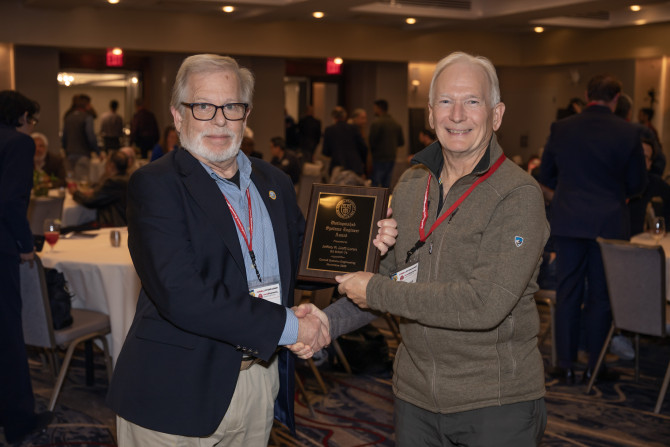 two people shake hands and hold a plaque
