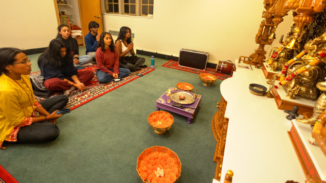 Members of the Hindu community chant in the temple room.