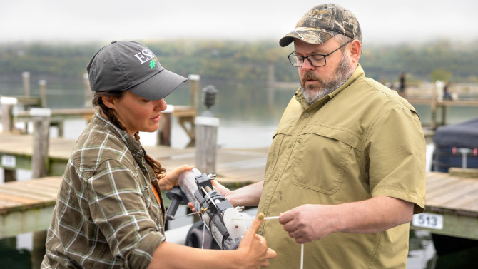 Erin Hassett from the State University of New York College of Environmental Science and Forestry and Jed Sparks, professor of ecology and evolutionary biology in the College of Arts and Sciences, prepare a Niskin bottle to be dropped into Seneca Lake in September to take water samples.