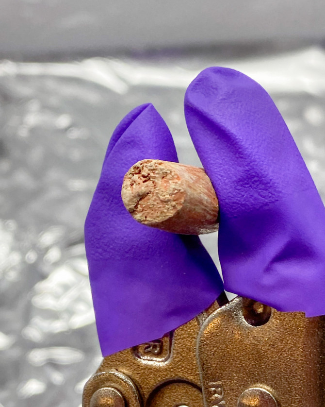 A ceramic sample is shown after incubation, with soil crust on its exterior.