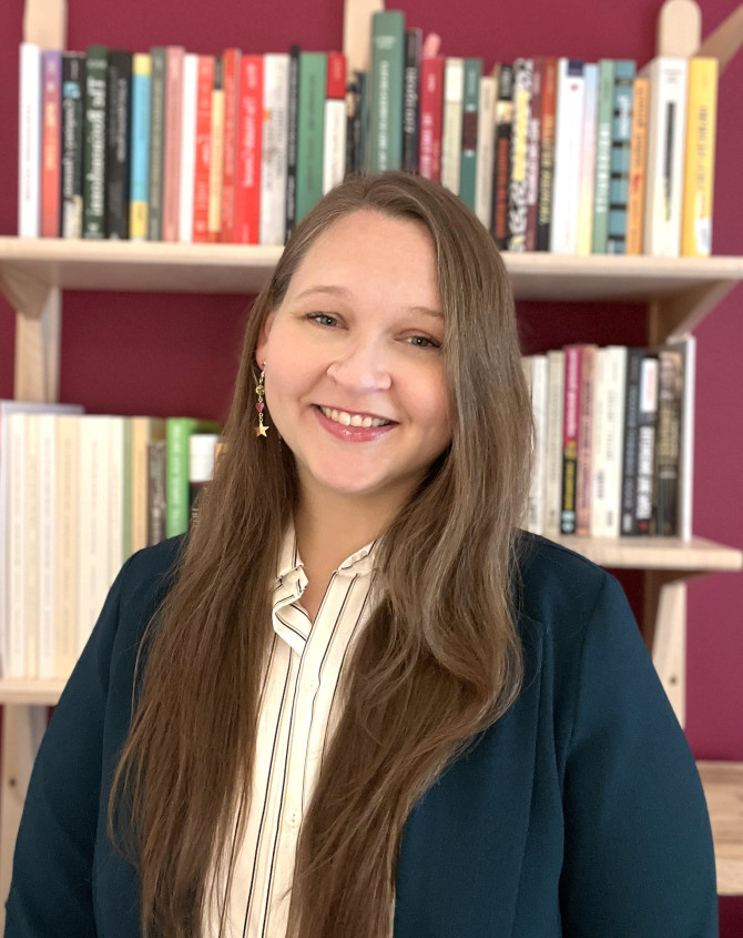 Dusti Bridges sits in front of a full bookshelf