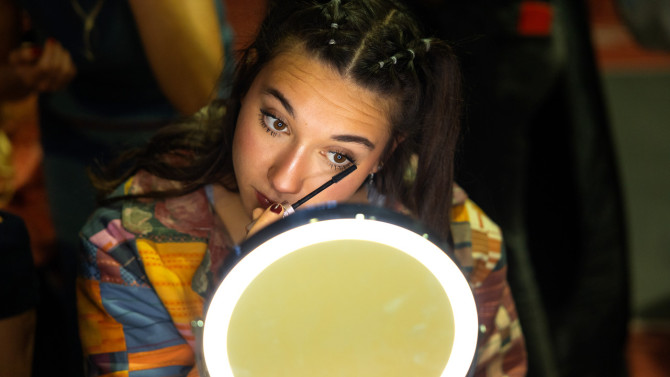 A model does her makeup before walking the runway.