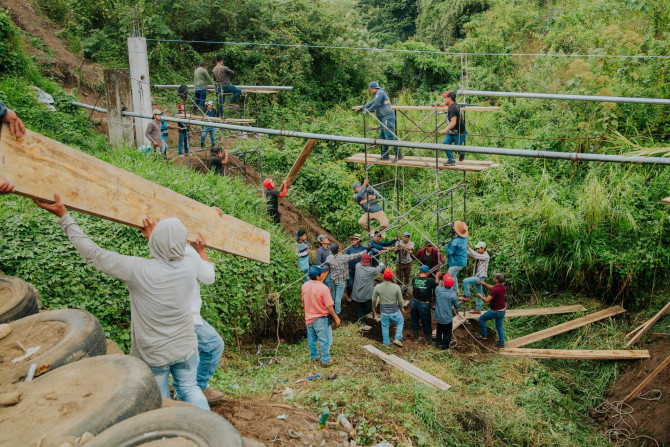 people suspending water pipes over a valley