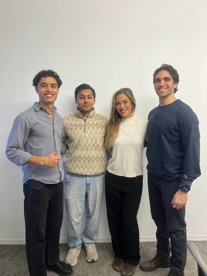 four people standing in front of a wall