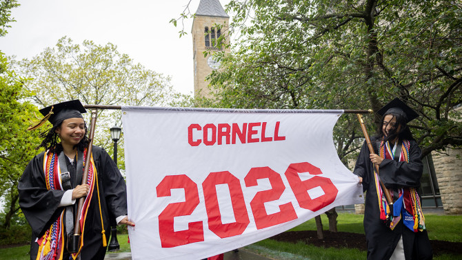 Two  students carrying the Cornell 2026 banner. 