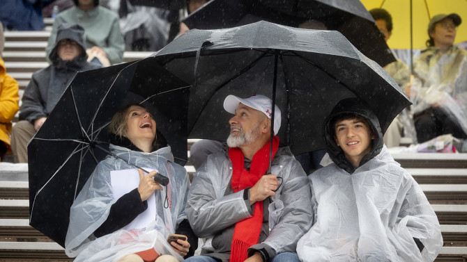 A family in the stands under umbrellas. 