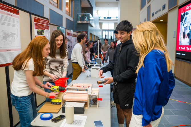 four students examine a device at a table