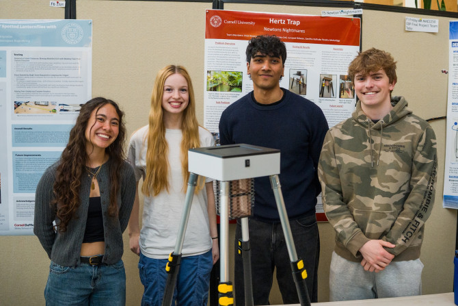four students stand behind a prototype