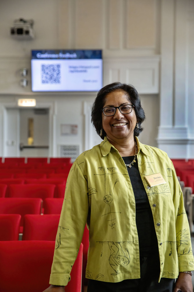 A woman in a green shirt smiles at the camera