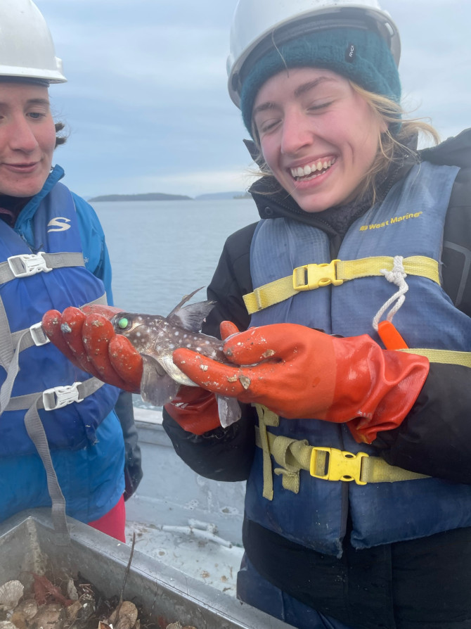 Anna Mehlhorn, wearing a life vest and gloves on a research boat, holds a deep-sea spotted ratfish collected off the coast of San Juan Island, Washington.
