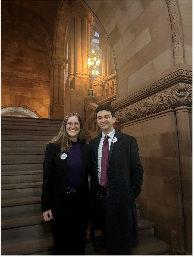 Hattie Seten and Rafael Montán standing in front of a flight of stone stairs in the NY State Capitol Building 