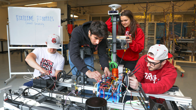 Andrew James ’26 (from left), Neil Morrison ’28, Natalia Kurz ’29 and Michael Neiss ’27 work on a prototype of their weed-killing robot ahead of The Farm Robotics Challenge, which they won on May 21.