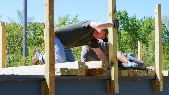 Todd Bittner, director of natural areas for Cornell Botanic Gardens, installs decking on the Dryden Rail Trail bridge designed by Cornell students. Bittner first recruited Charlie Trautmann, adjunct associate professor, and students to help with another bridge project, which led to the creation of the Engineering in the Community course.