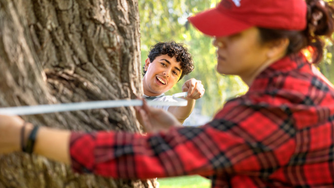 Jayden Camarena (left), master's student in landscape architecture, and Fatima Bouzid (right), master's student in public administration, take measurements of a large tree in Stewart Park on July 1. 