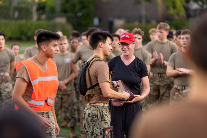 woman wearing Cornell cap receiving a ceremonial flag