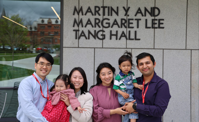 two couples hold children