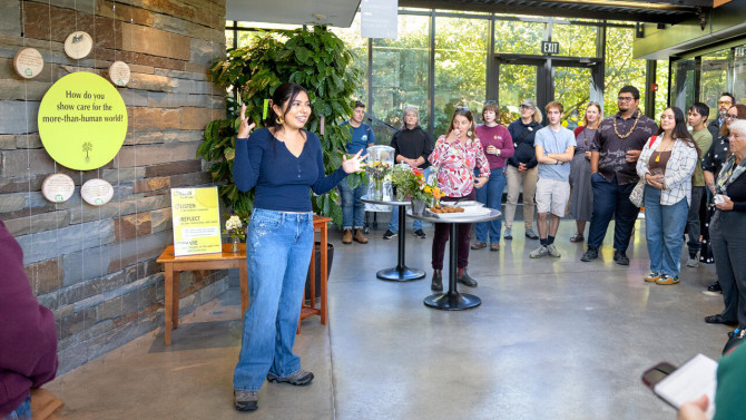 Shania Flores ’28, a student interpretation assistant with the botanic gardens, speaks in front of the Rooted in Reciprocity exhibit at an opening celebration Oct. 3.