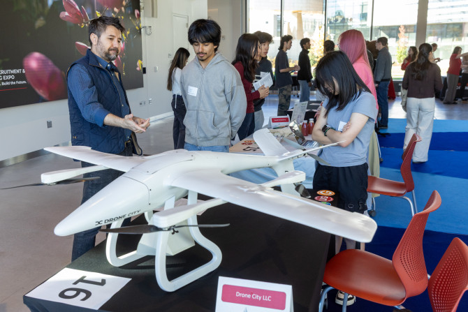 person showing off a drone to a student at a career fair