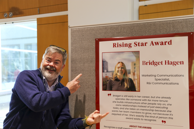 Man pointing at photo of award winner