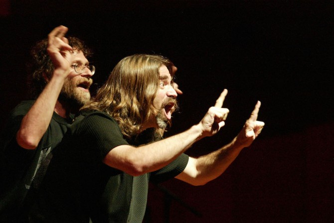 Two people perform with dramatic hand gestures and facial expressions