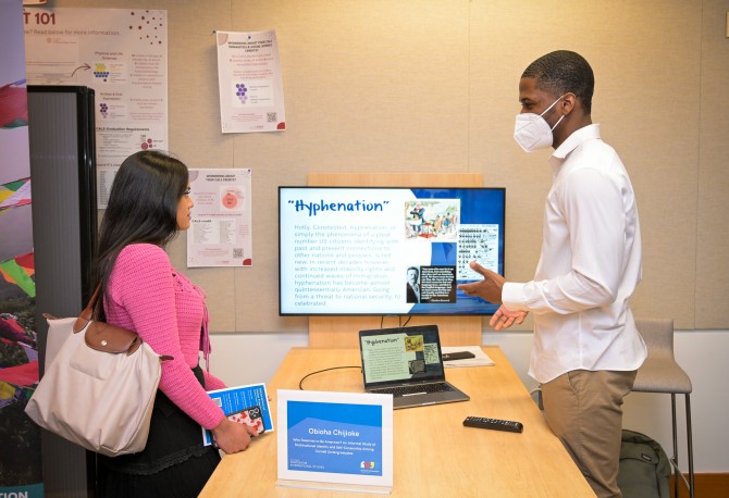 Student Obioha Chijioke presents a slide titled "Hyphenation" to a fellow student. 