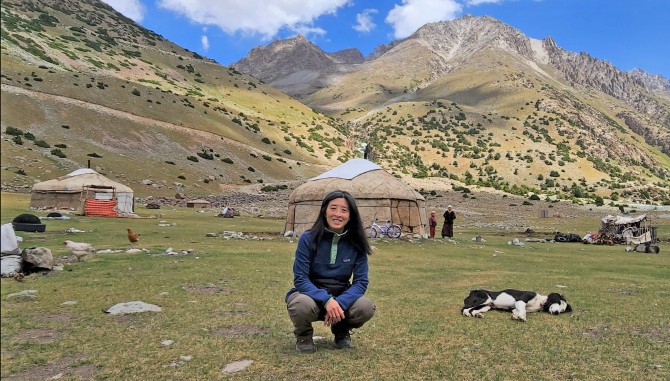 Helen Lee posing in front of yurts in mountains of Tajikistan.