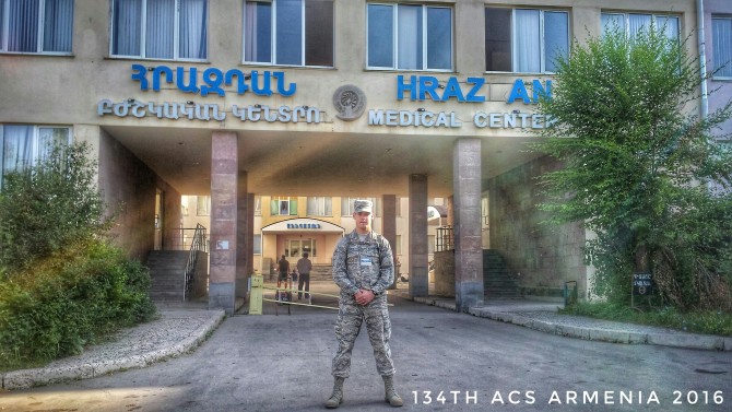 man in military uniform stands outside a hospital
