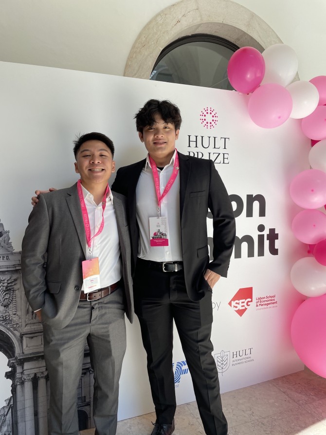 two people in front of Hult Prize sign
