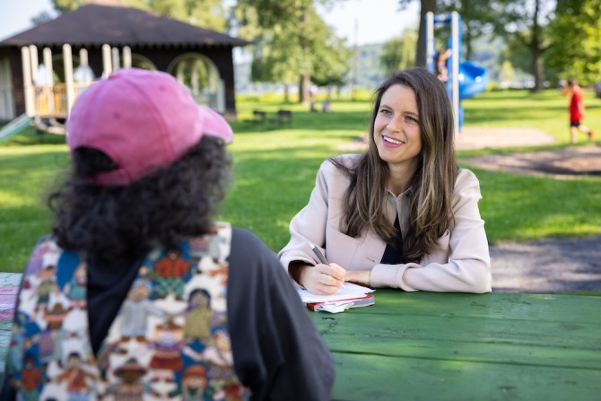 Two people sit at a table conversing outdoors
