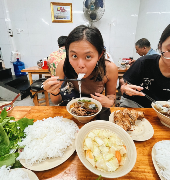 Dana Oshiro slurps noodles at a restaurant in Vietnam.