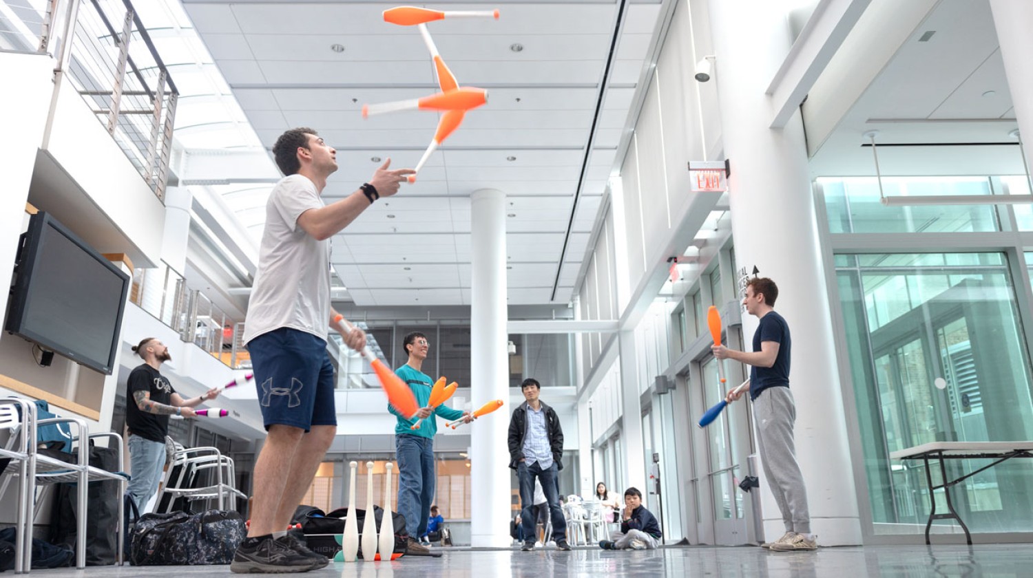 Cornell Juggling Club members practice with clubs during a weekly gathering in the Physical Sciences Building atrium. Jonah Botvinick-Greenhouse, second from left, and Bennett Santora ’26, far right, both have won elite juggling competitions.