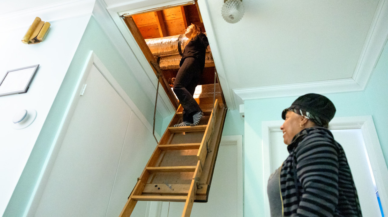 Suzette Foote (right) watches Shannon Fabiani inspect new upgraded insulation in Foote’s home.
