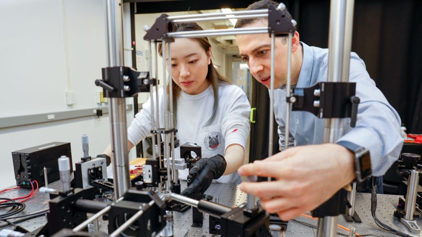 Assistant professor Mostafa Hassani (right) and doctoral student Qi Tang work with a custom-built platform to launch supersonic microprojectiles and study how high-speed metallic collisions form solid-state bonds.