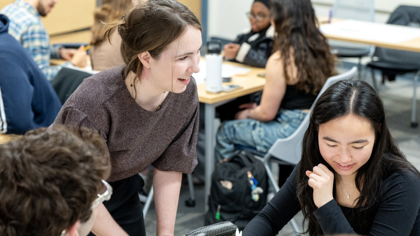A professor consults with her students as they work in groups.