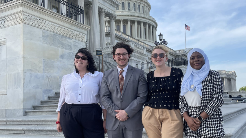 Four Cornell students stand on the steps in front of the Capitol