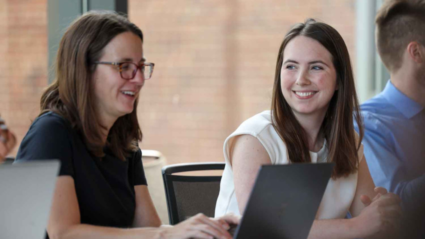 two people talking and working on computers