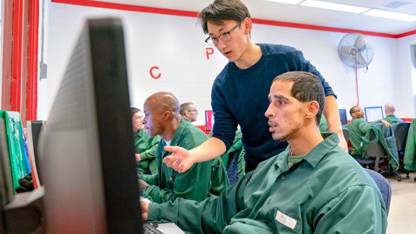 Edward Mei ’18 assists students in the Cornell Prisoner Education Program’s computer laboratory at the Cayuga Correctional Facility.