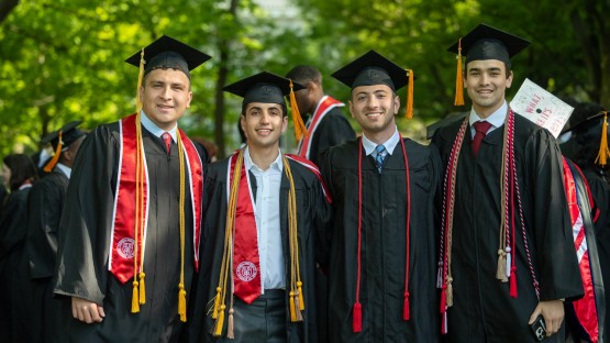 Four graduates pose in the Arts Quad.