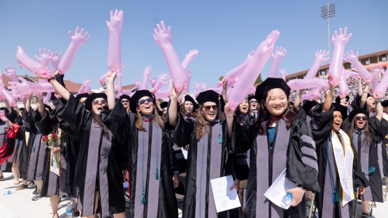 Graduates wave inflated gloves during the commencement ceremony.