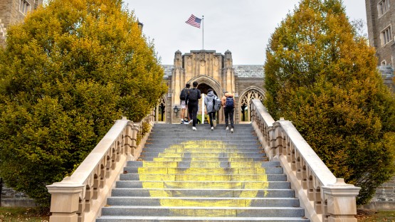 Students walk past a giant smiley face chalk art on West Campus.