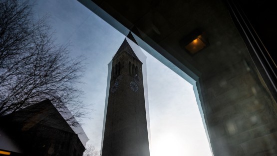 McGraw Tower is reflected in a window of Olin Library.